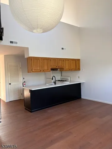 a living room with stainless steel appliances kitchen island granite countertop a sink wooden cabinets and granite counter tops
