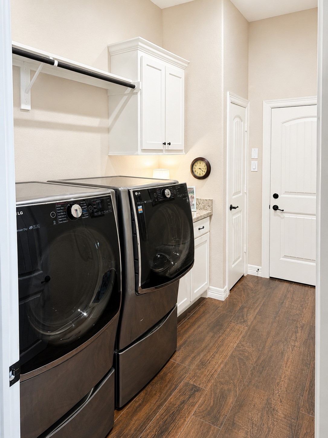 27656 Rio Blanco Drive Splendora, TX 77372 - Photo 18 of 18 A modern, spacious laundry room. It features white cabinetry, a countertop, and a hanging rod for convenience. The room has a warm wood-look flooring and neutral walls, creating a clean and functional space.