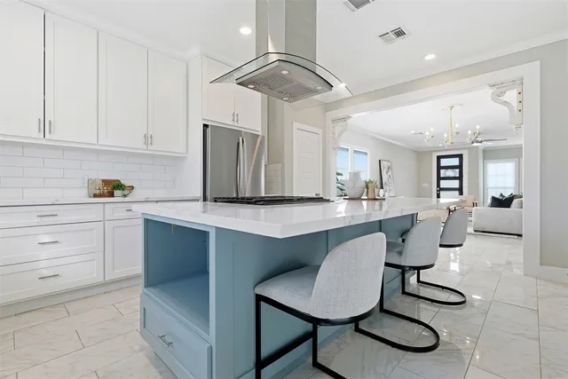 a kitchen with stainless steel appliances kitchen island a table chairs in it and white cabinets