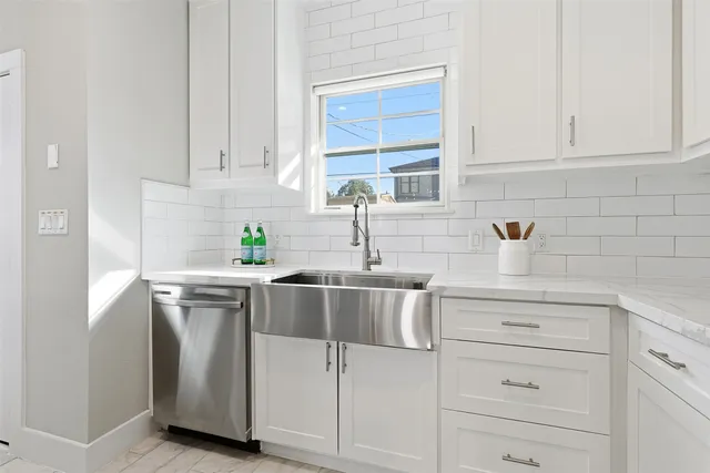 a kitchen with white cabinets and sink