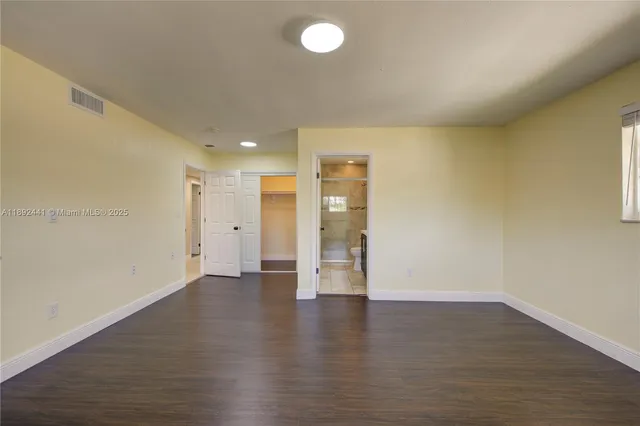 a view of an empty room with wooden floor and windows