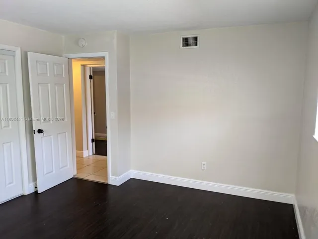 an empty room with wooden floor & windows