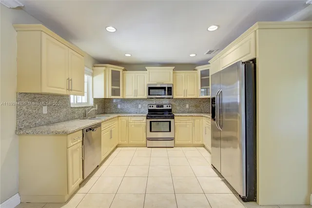 a kitchen with stainless steel appliances granite countertop a stove a sink and a refrigerator