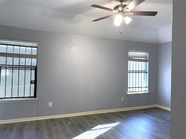 an empty room with windows and fan