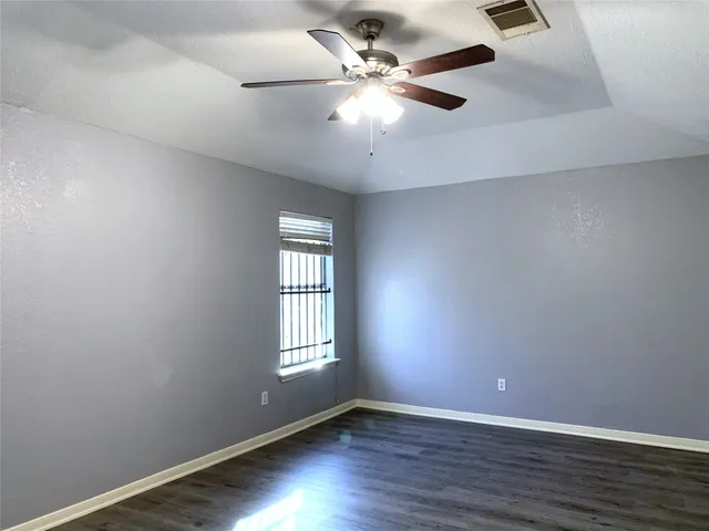 an empty room with wooden floor fan and windows