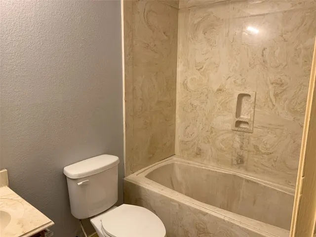 a white toilet and tub sitting next to a bathroom sink