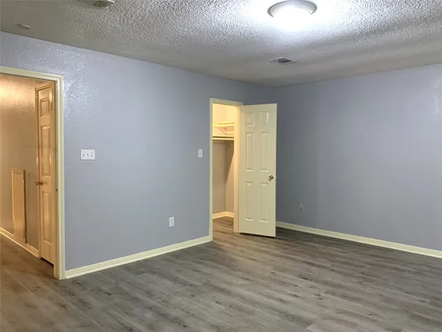 a view of an empty room with wooden floor and closet