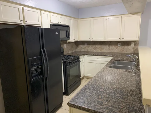 a kitchen with stainless steel appliances granite countertop a refrigerator a stove and a sink