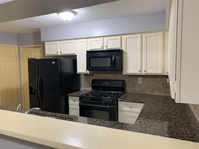 a kitchen with granite countertop a refrigerator and a stove top oven