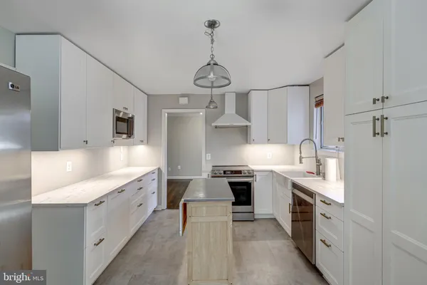 a large kitchen with stainless steel appliances granite countertop a sink stove oven and white cabinets