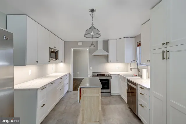 a large kitchen with stainless steel appliances granite countertop a sink stove oven and white cabinets