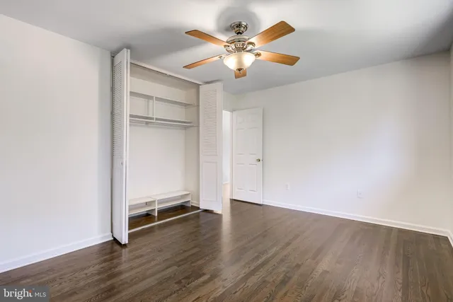 an empty room with wooden floor and chandelier fan