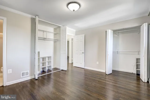 an empty room with wooden floor closet and windows
