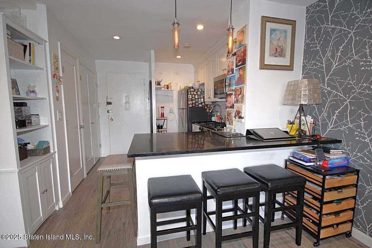 1000 Clove Road, Unit 7G Staten Island, NY 10301 - Photo 5 of 16 a kitchen with stainless steel appliances kitchen island granite countertop a table and chairs
