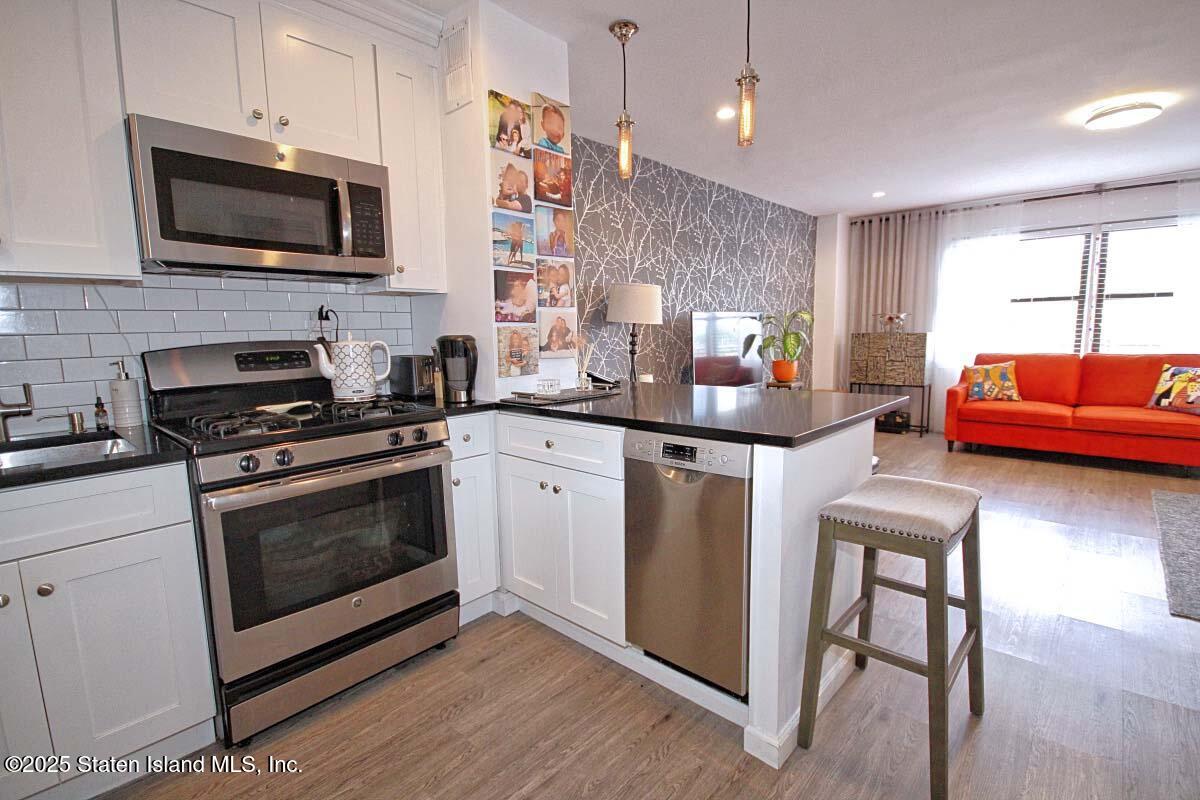 1000 Clove Road, Unit 7G Staten Island, NY 10301 - Photo 7 of 16 a kitchen with stainless steel appliances a stove microwave and sink