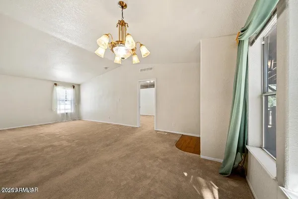 a view of a livingroom with a chandelier fan and windows