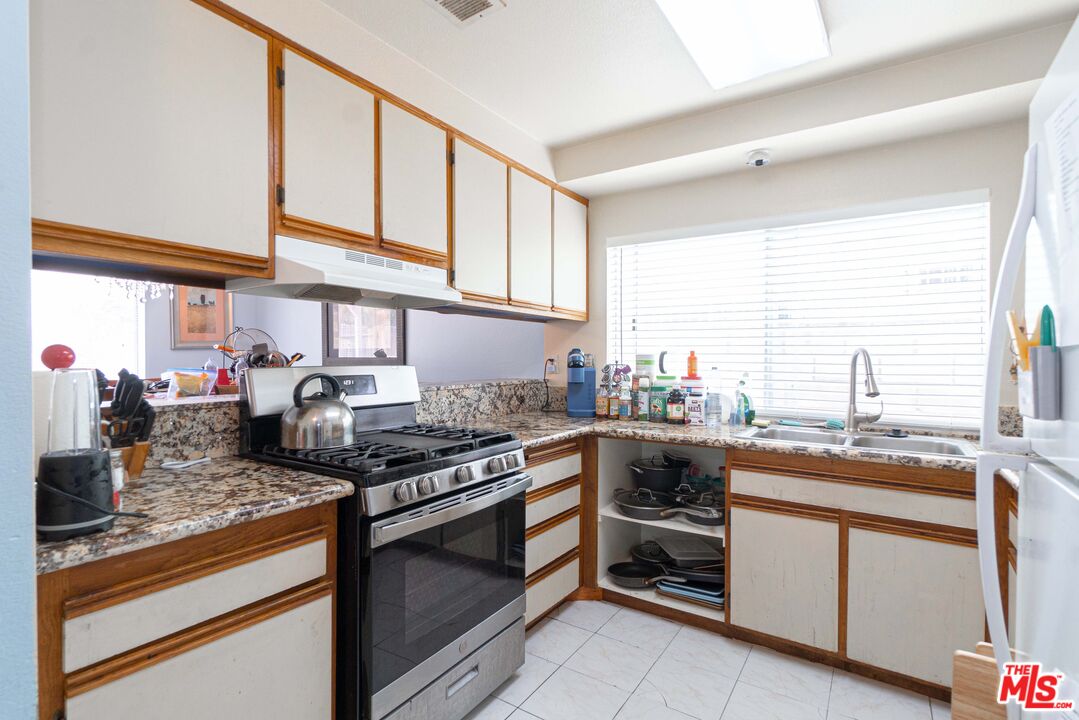 724 Anzac Circle Compton, CA 90220 - Photo 3 of 16 a kitchen with stainless steel appliances granite countertop a stove a sink and a microwave
