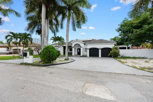 a view of a house with a yard and palm trees
