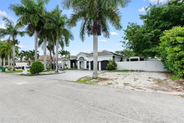 a front view of a house with a garden and palm trees