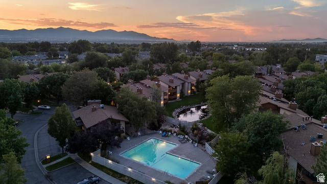 6852 Countrywoods Circle, Unit 5D Midvale, UT 84047 - Photo 48 of 50 Expansive community grounds featuring a swimming pool, mature landscaping, a tranquil pond, and mountain scenery