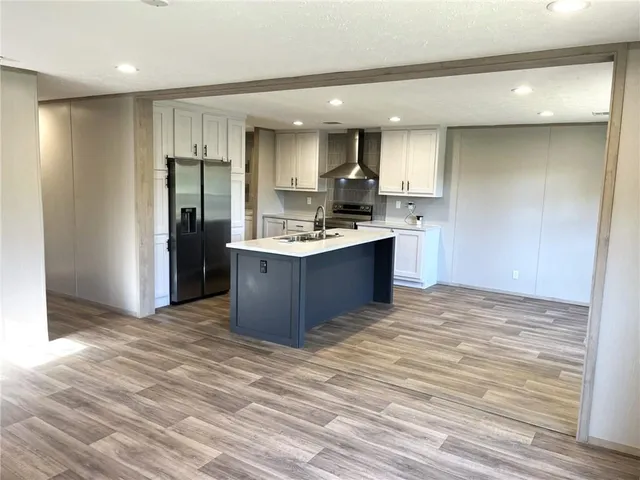 a kitchen with stainless steel appliances kitchen island a sink refrigerator and cabinets