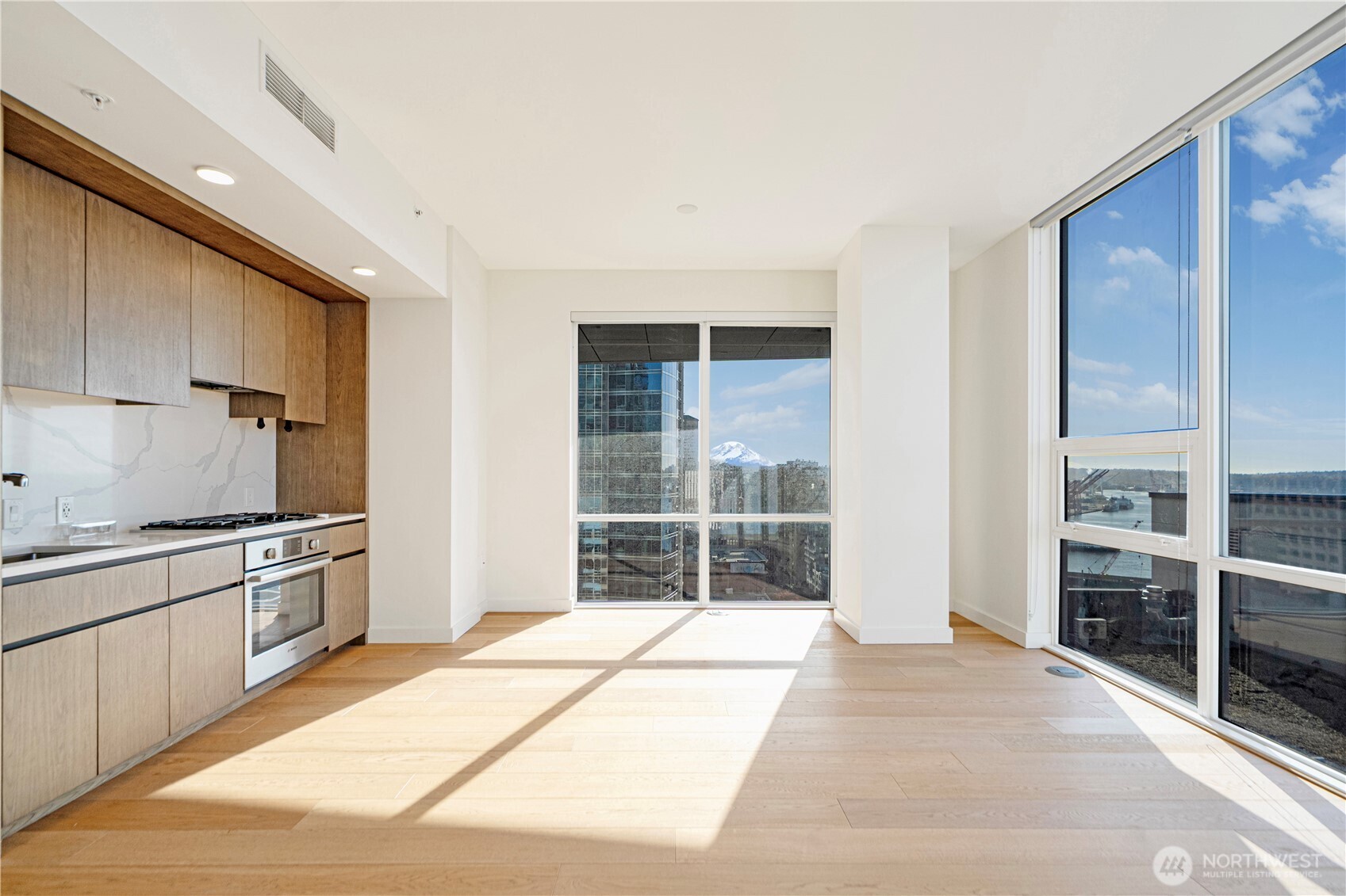 121 Stewart Street, Unit 1605 Seattle, WA 98101 - Photo 2 of 38 a kitchen with stainless steel appliances kitchen island granite countertop a stove a sink and white cabinets