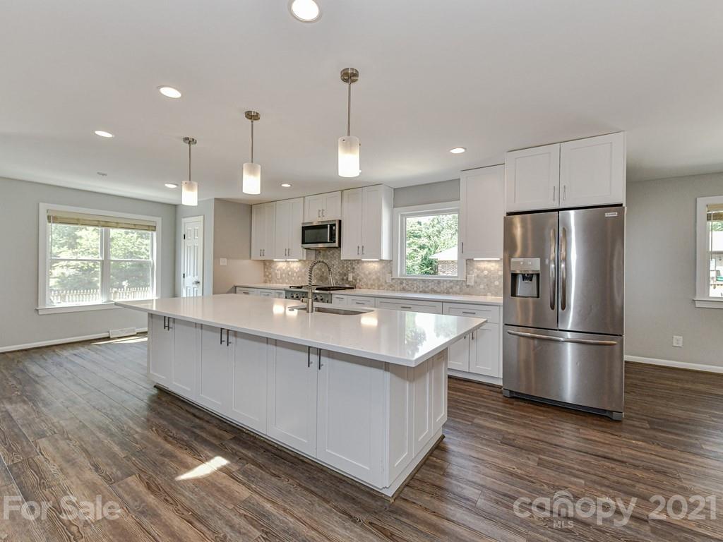 305 Boyce Road Charlotte, NC 28211 - Photo 13 of 48 a large kitchen with stainless steel appliances kitchen island granite countertop a refrigerator a sink dishwasher a s stove top oven a large island with wooden floor and cabinets