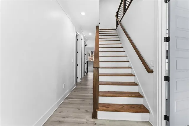 a view of a hallway with wooden floor and a bathroom