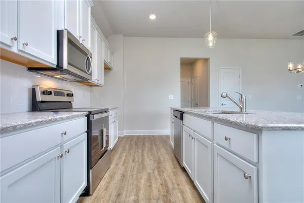 a kitchen with stainless steel appliances granite countertop a sink and dishwasher a stove top oven with wooden floor