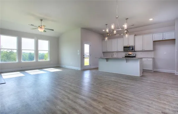 an empty room with wooden floor a kitchen view and a kitchen