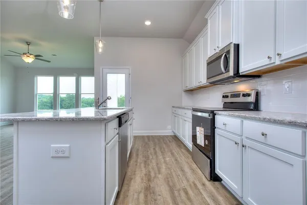 a kitchen with stainless steel appliances granite countertop a stove a sink and a microwave