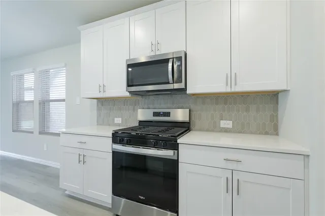 a kitchen with white cabinets and black appliances
