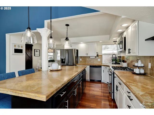 a kitchen with stainless steel appliances granite countertop a sink a stove and a refrigerator