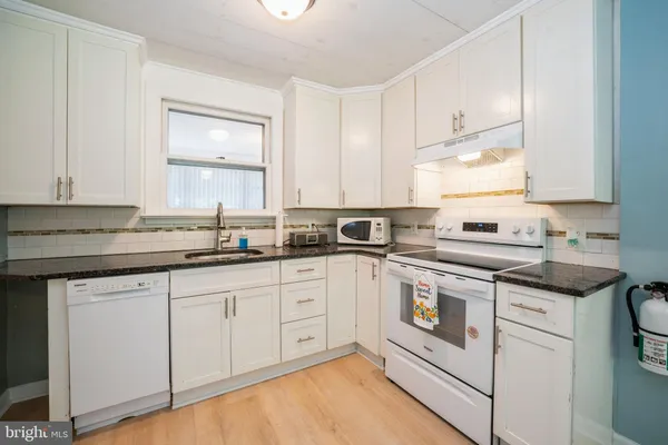 a kitchen with granite countertop white cabinets and white appliances