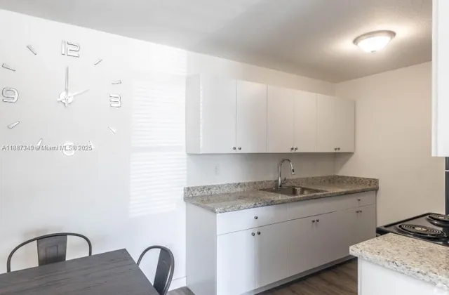 a kitchen with stainless steel appliances granite countertop a sink a stove and white cabinets