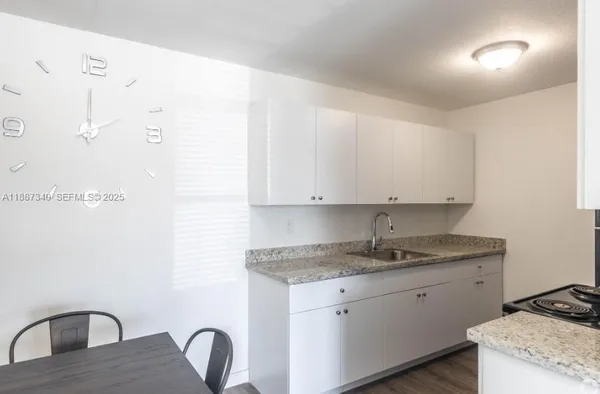 a kitchen with stainless steel appliances granite countertop a sink a stove and white cabinets