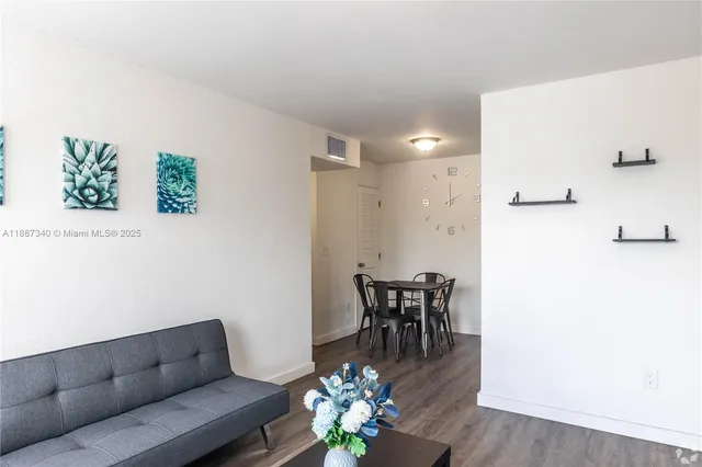 a living room with furniture and a dining table with wooden floor