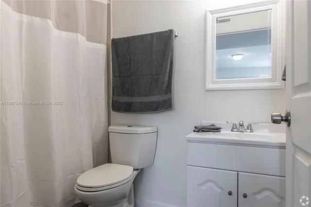 a bathroom with a toilet sink vanity and mirror