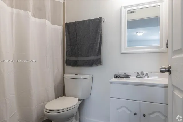 a bathroom with a toilet sink vanity and mirror