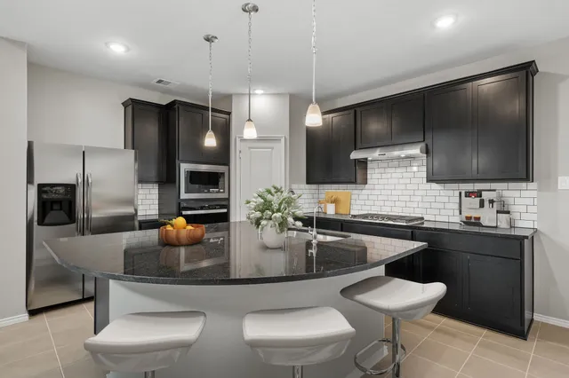 a kitchen with stainless steel appliances a dining table chairs sink and living room view