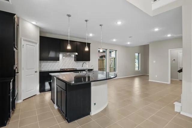 a kitchen with kitchen island granite countertop a sink and a stove top oven with wooden floor