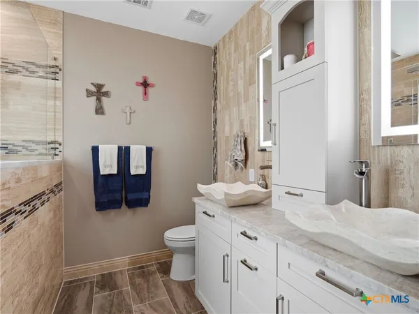 a spacious bathroom with a granite countertop sink a toilet and a shower curtain