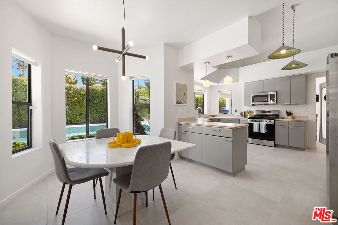 1414 Sagebrush Road Palm Springs, CA 92264 - Photo 23 of 48 a kitchen with a table chairs refrigerator and microwave