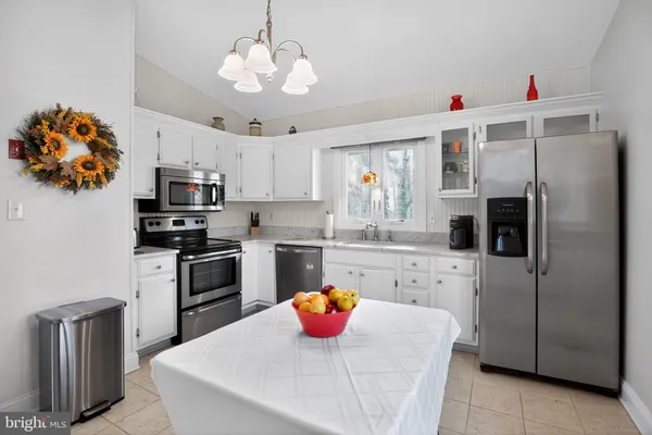 a kitchen with stainless steel appliances a stove a refrigerator and a chandelier