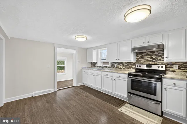 a kitchen with granite countertop a stove cabinets and wooden floor
