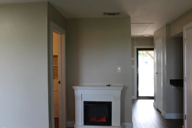 a view of an empty room with wooden floor and a fireplace