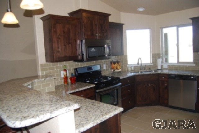 167 Red Rocks Street Fruita, CO 81521 - Photo 4 of 9 a kitchen with granite countertop a sink a stove and a wooden cabinets