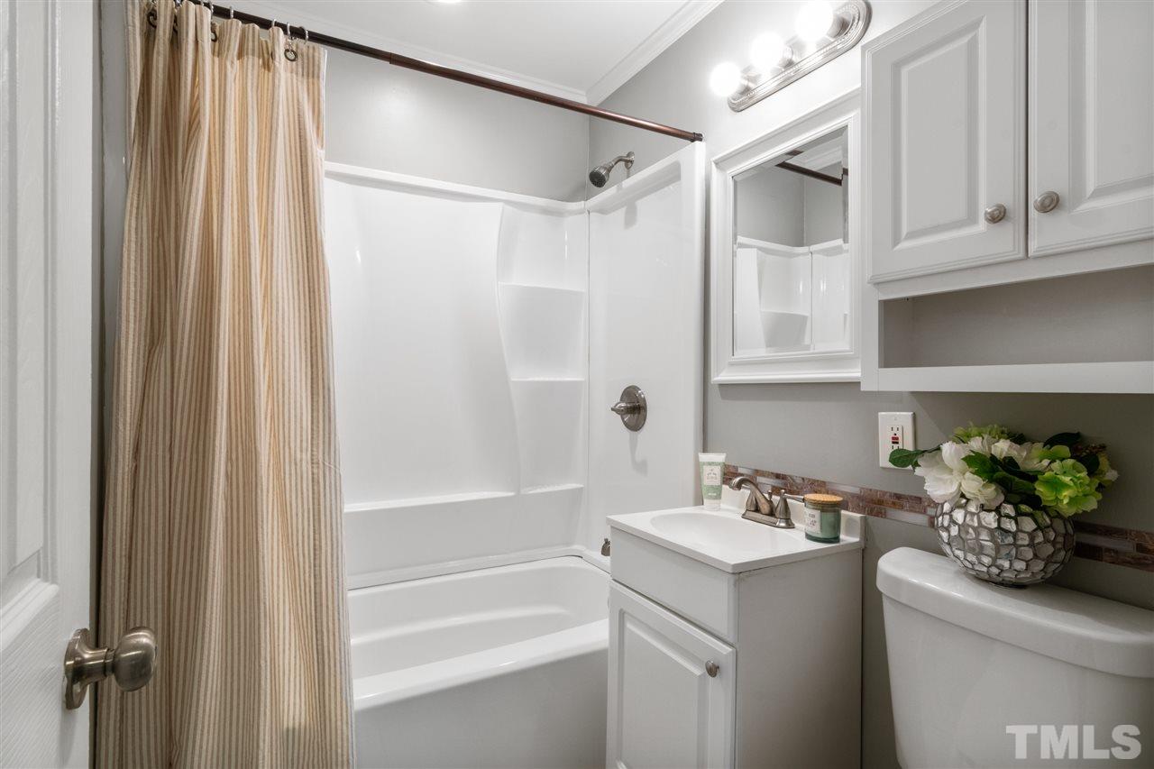701 Hadley Road Raleigh, NC 27610 - Photo 9 of 16 a bathroom with a sink a mirror and a shower