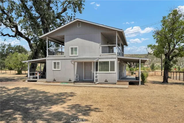 a view of house with backyard and trees in the background