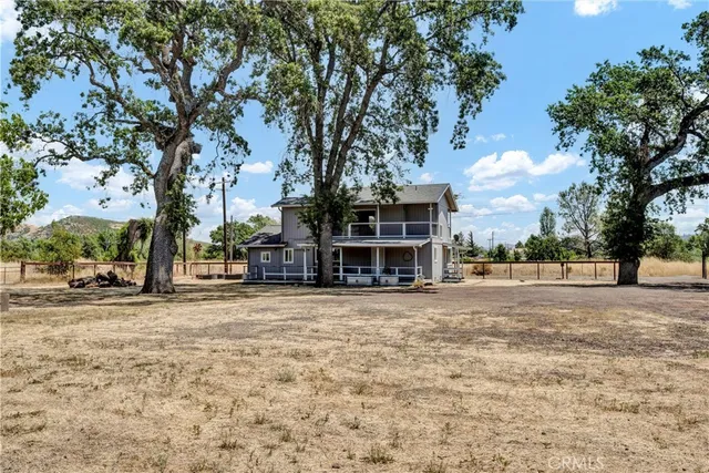a view of a house with a yard and large trees
